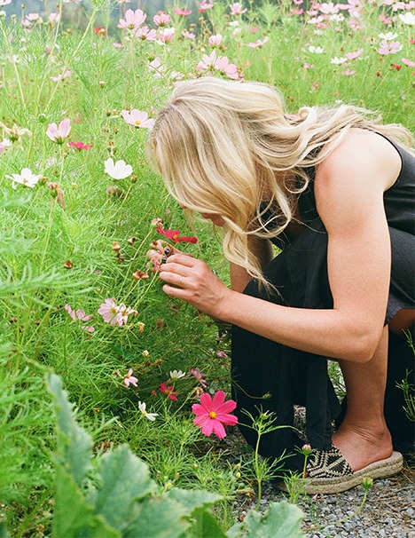 A Woman Kneels Among Colorful Flowers in a Vibrant Field, Enjoying the Beauty of Nature.